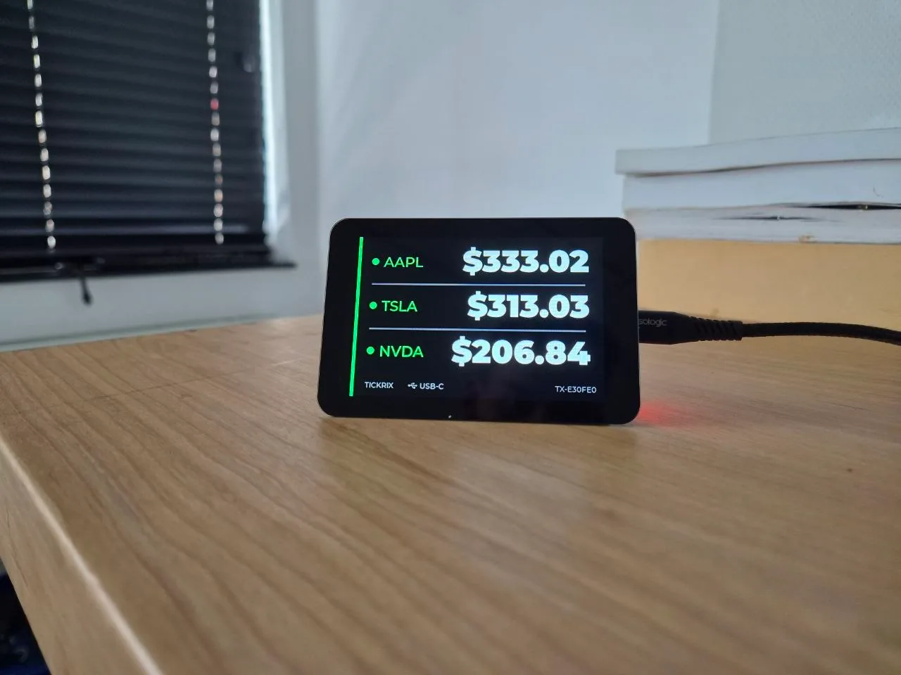 A Tickrix desk display showing live AAPL, TSLA and NVDA share prices side by side